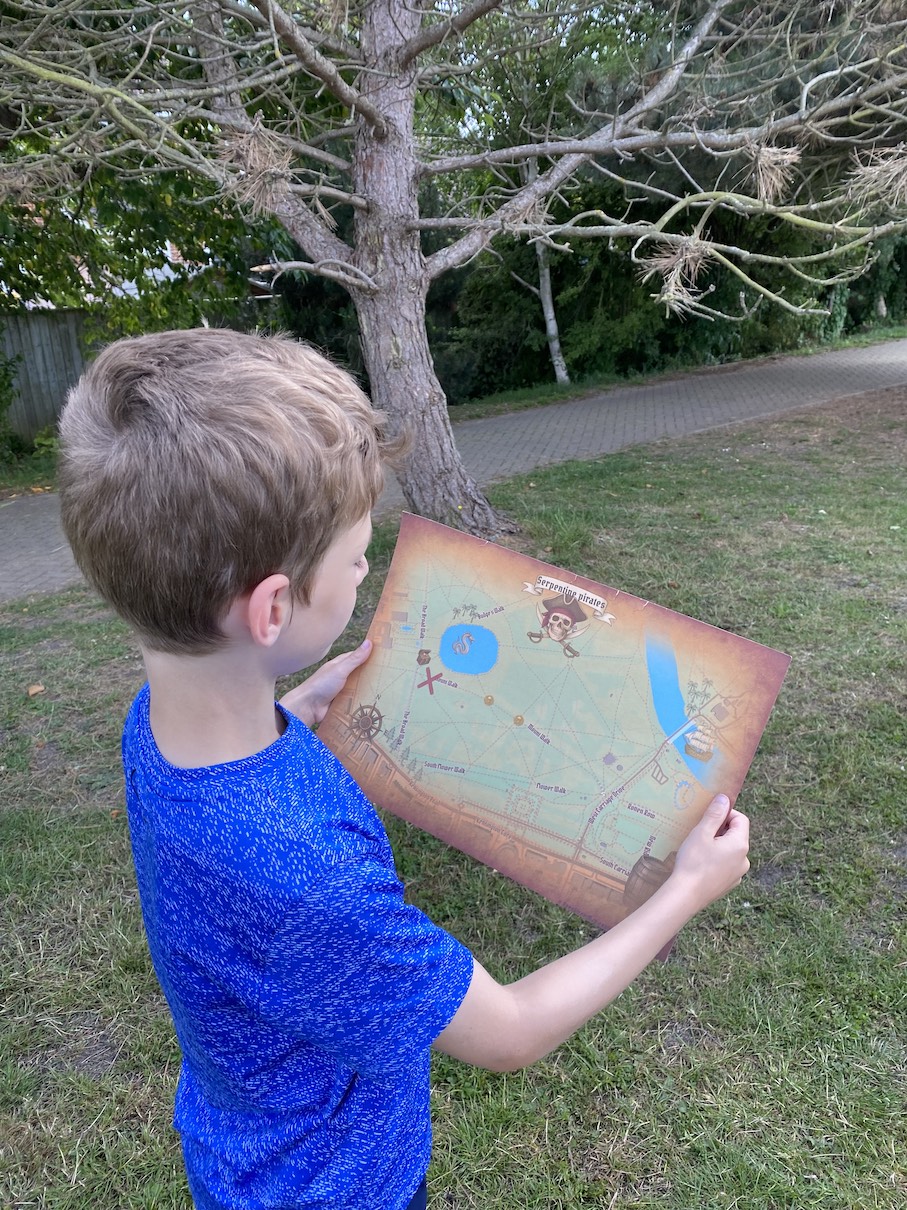 My son holding a printed treasure map from the app in the park